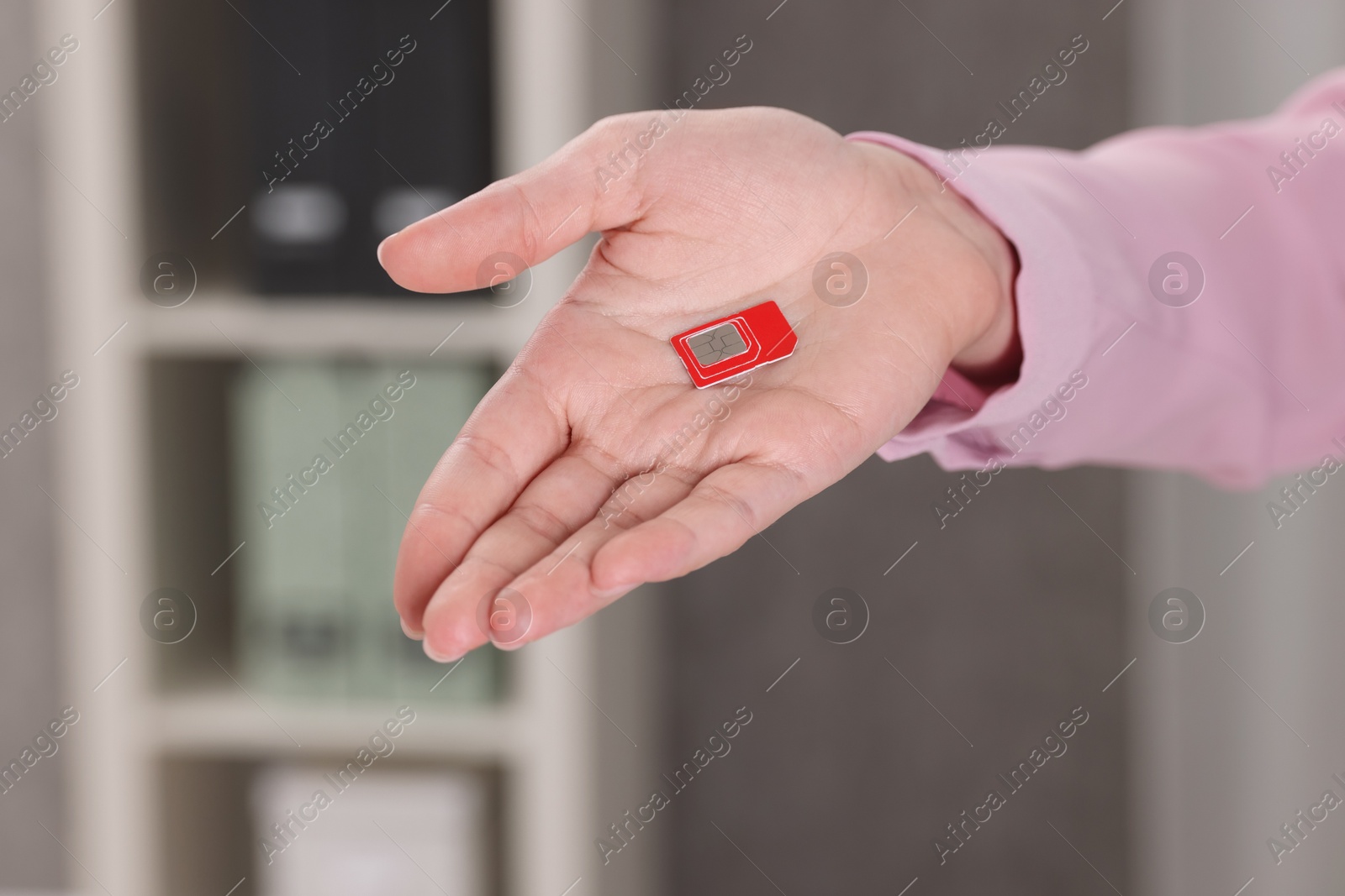 Photo of Woman holding SIM card indoors, closeup view