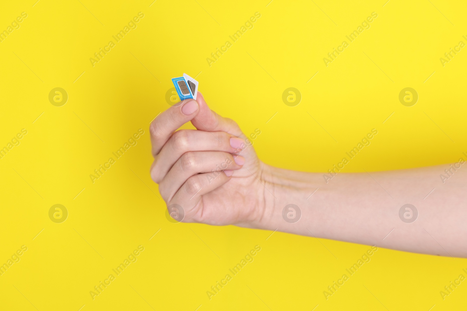 Photo of Woman holding SIM cards on yellow background, closeup