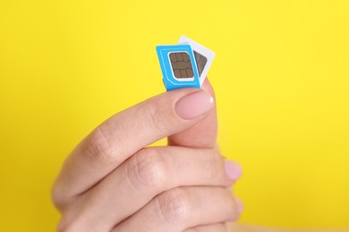 Photo of Woman holding SIM cards on yellow background, closeup