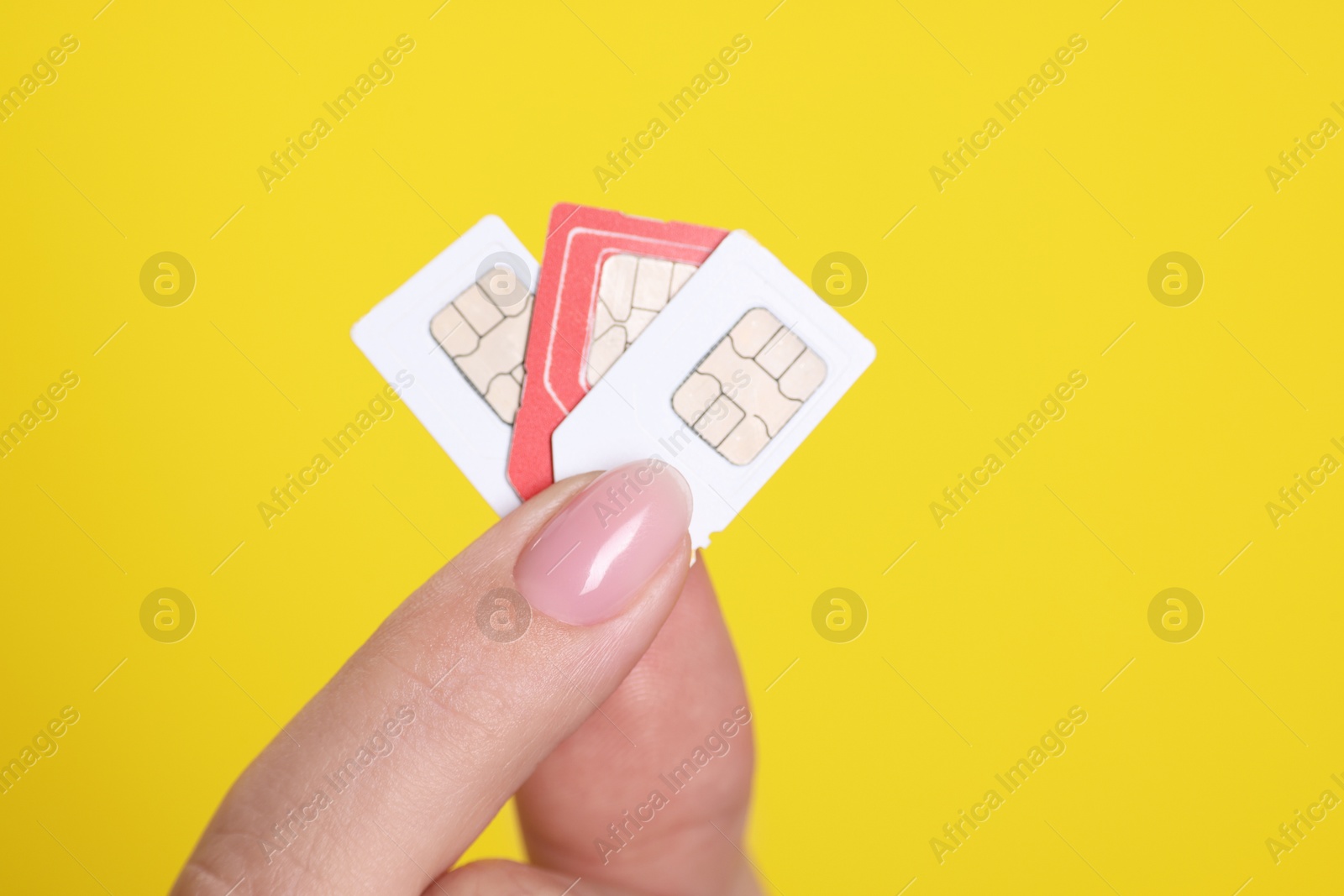 Photo of Woman holding SIM cards on yellow background, closeup