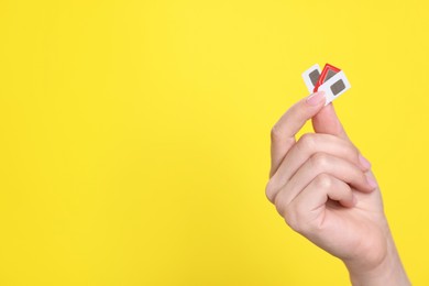 Photo of Woman holding SIM cards on yellow background, closeup. Space for text