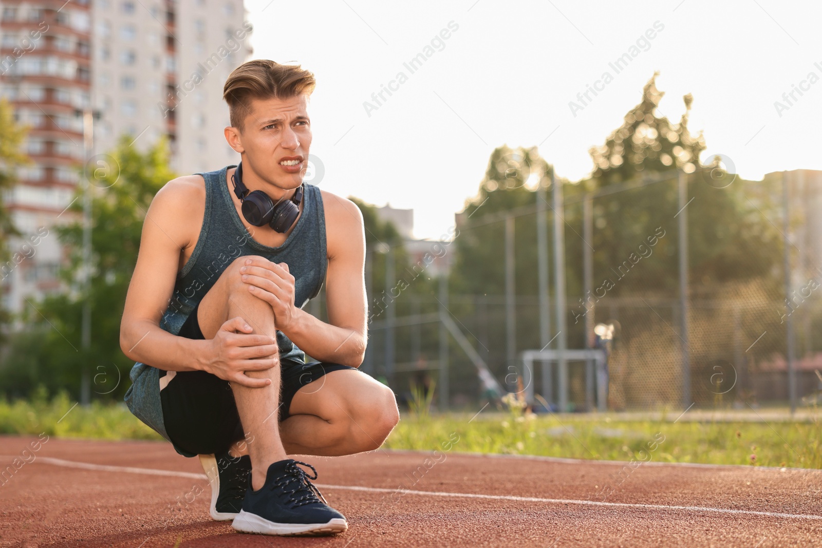 Photo of Sportsman with leg injury suffering from knee pain at stadium, space for text