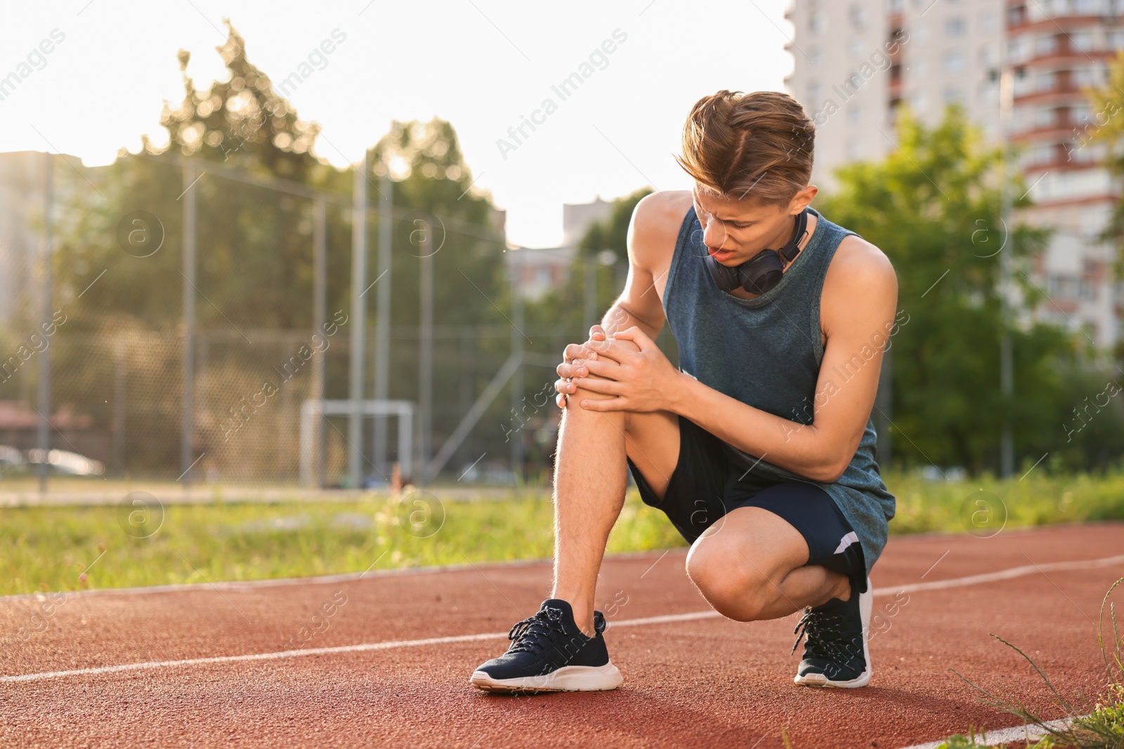 Photo of Sportsman with leg injury suffering from knee pain at stadium, space for text