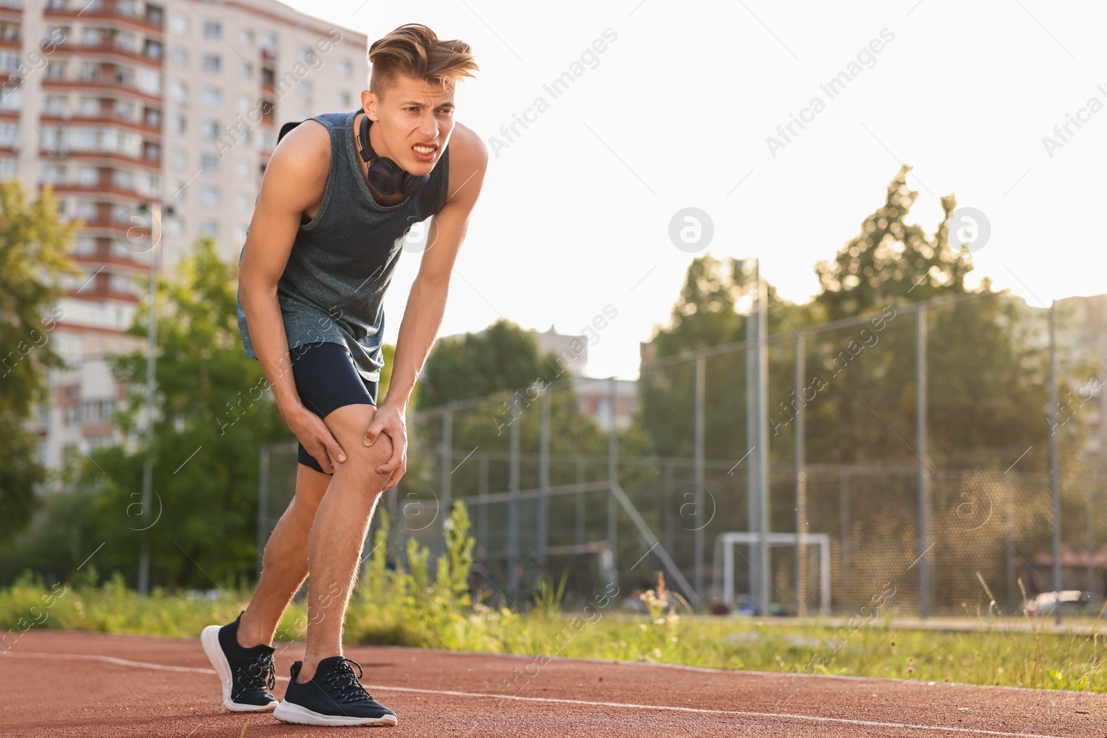 Photo of Sportsman with leg injury suffering from knee pain at stadium, space for text