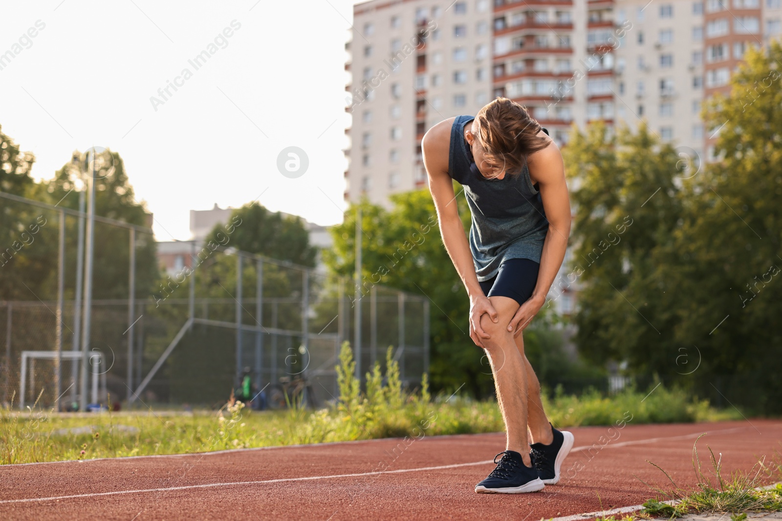 Photo of Sportsman with leg injury suffering from knee pain at stadium, space for text