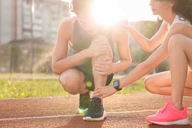 Sports injury. Woman helping man with leg pain at stadium