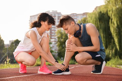 Sports injury. Woman helping man with leg pain at stadium