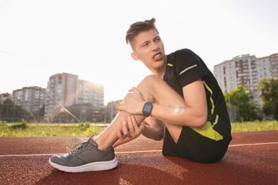 Sportsman with injured leg at stadium on sunny day