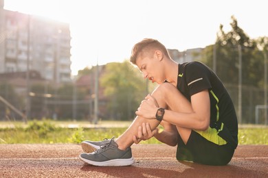 Sportsman with leg injury at stadium, space for text