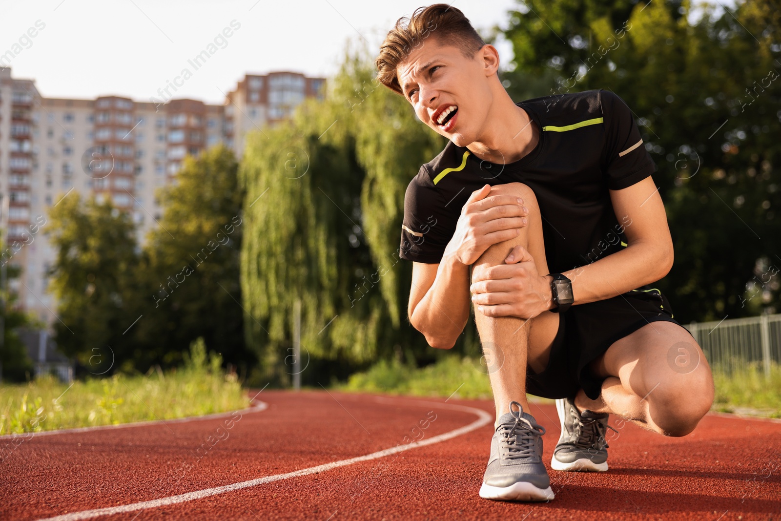 Photo of Sportsman with leg injury suffering from knee pain at stadium, space for text