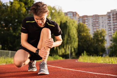 Sportsman with leg injury at stadium, space for text