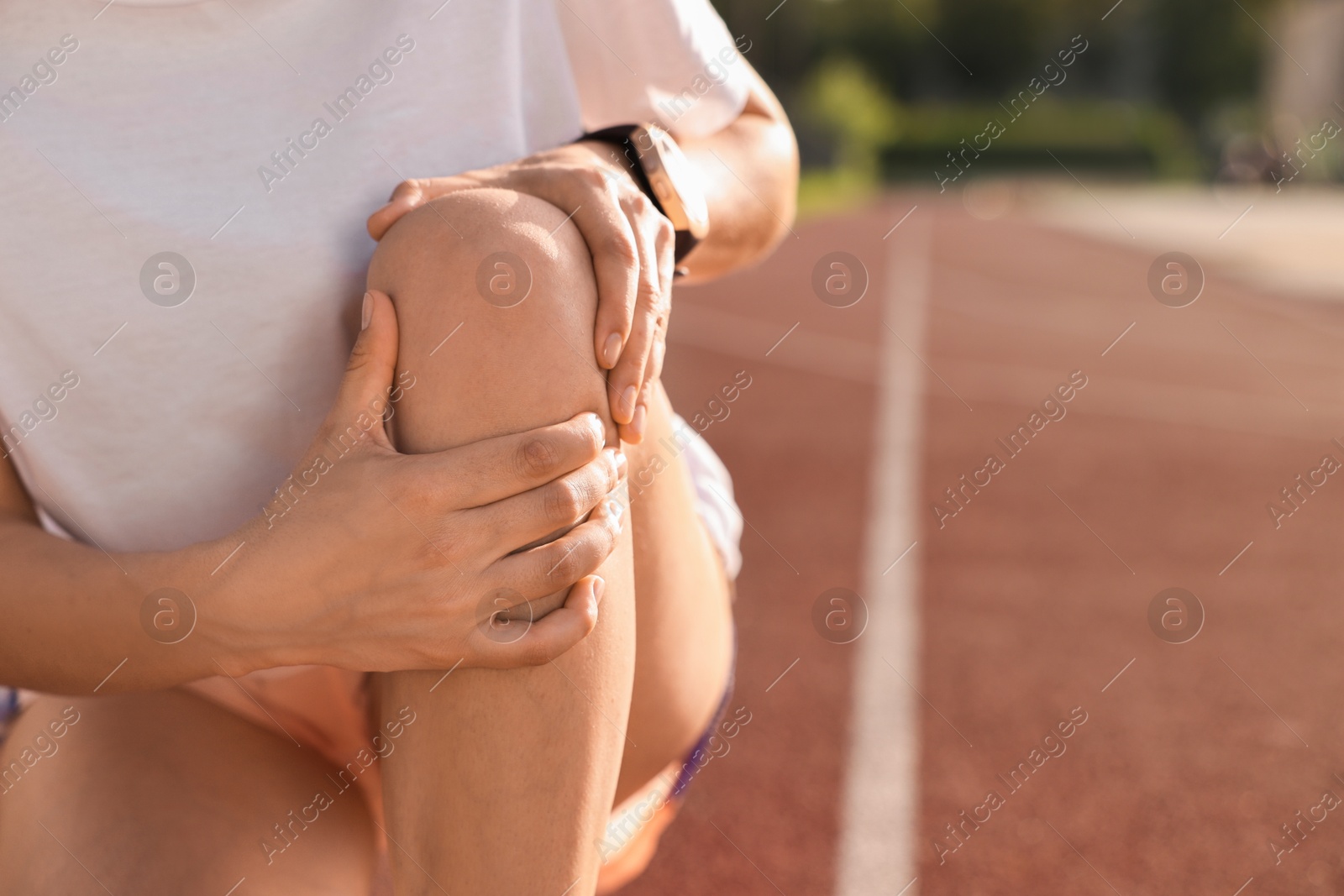 Photo of Sportswoman with leg injury suffering from knee pain at stadium, closeup. Space for text