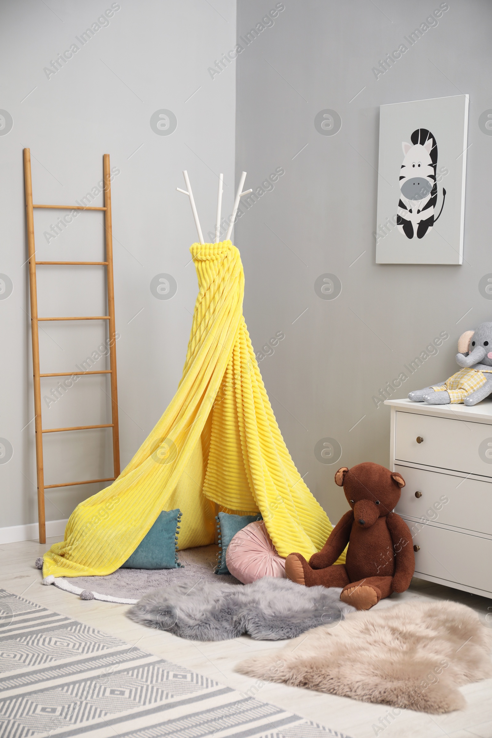 Photo of Play tent, toys, chest of drawers and picture in child room. Interior design