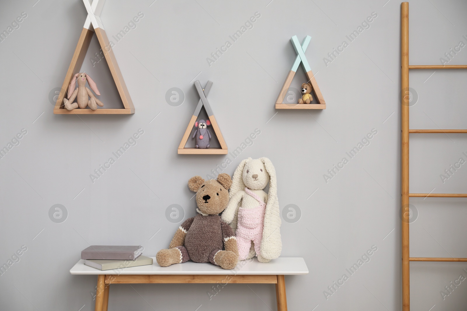 Photo of Stylish child room interior with console table, shelves, toys and ladder