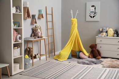 Stylish child room interior with modern furniture, toys and play tent