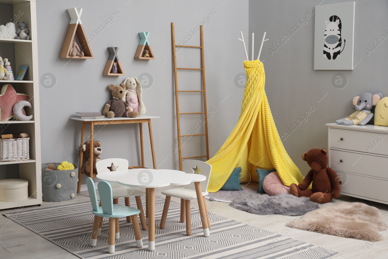 Photo of Stylish child room interior with table, chairs, toys and play tent