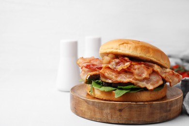 Photo of Delicious burger with bacon and greens on white tiled table. Space for text