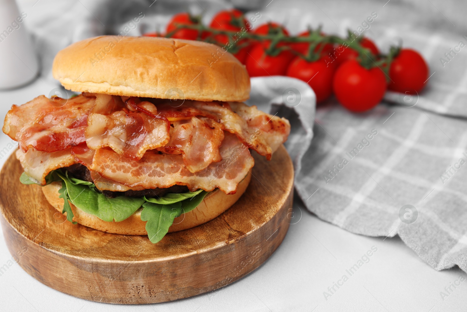 Photo of Delicious burger with bacon and greens on white table, closeup