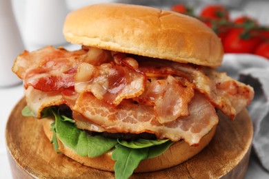 Photo of Delicious burger with bacon and greens on table, closeup