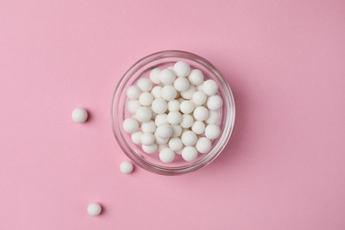 Homeopathic remedy. Pills in glass bowl on pink background, top view