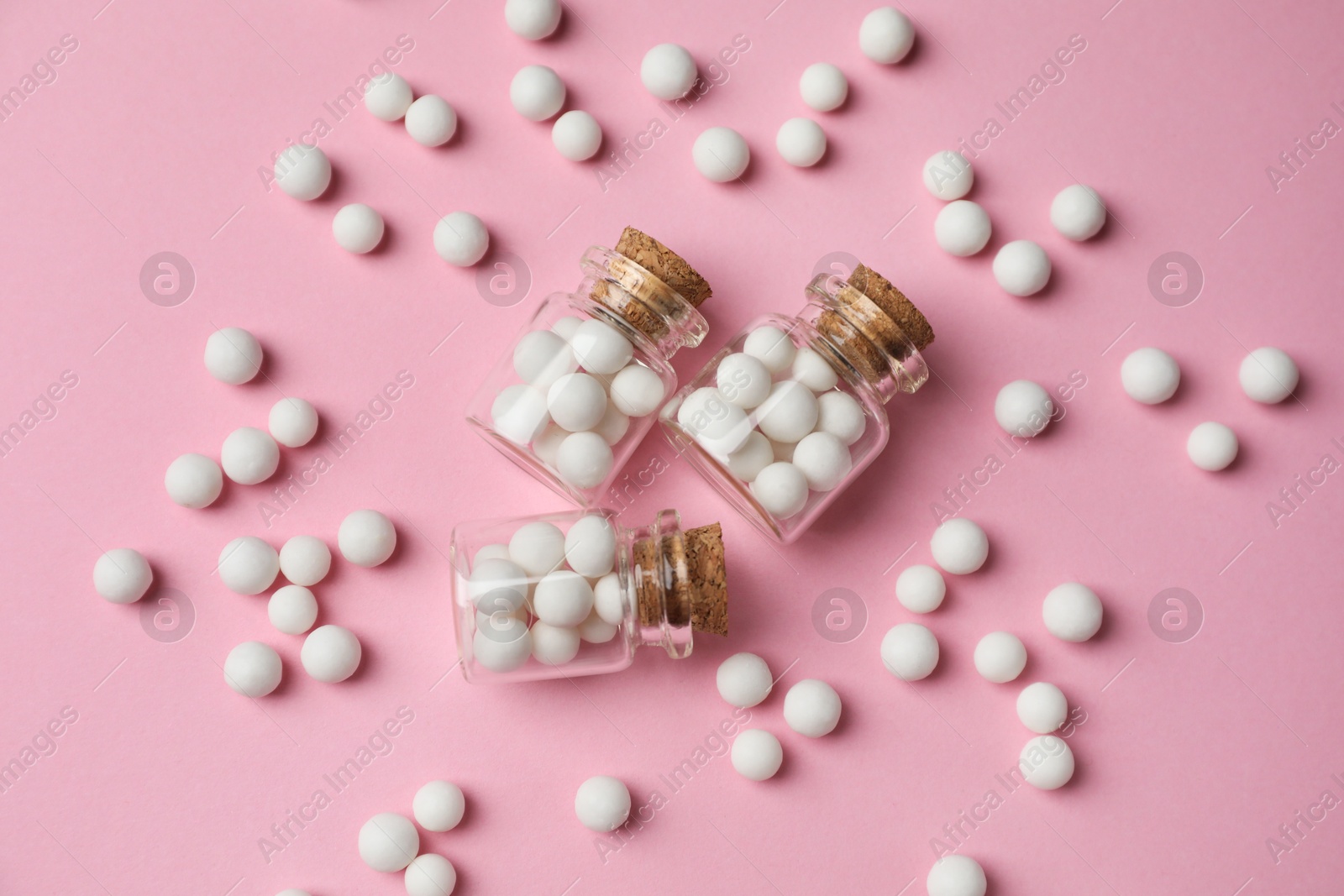 Photo of Homeopathic remedy. Glass bottles and pills on pink background, flat lay