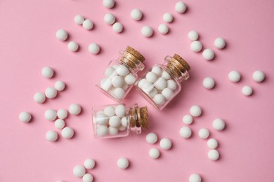 Photo of Homeopathic remedy. Glass bottles and pills on pink background, flat lay