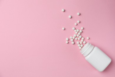 Photo of Homeopathic remedy. Overturned plastic bottle and pills on pink background, top view. Space for text