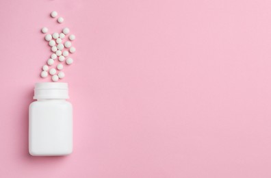 Photo of Homeopathic remedy. Overturned plastic bottle and pills on pink background, top view. Space for text