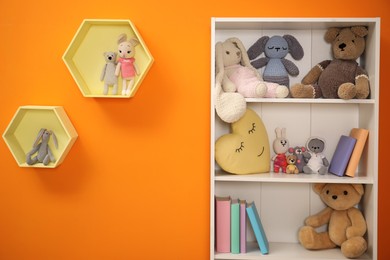 Photo of Shelves with different toys on orange wall in child room