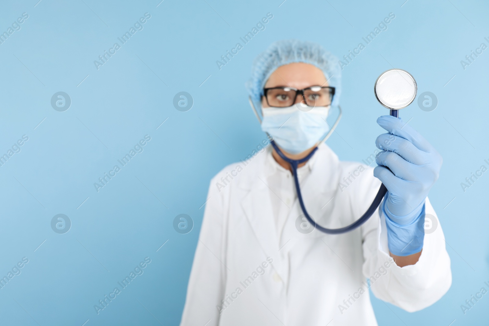 Photo of Doctor holding stethoscope on light blue background, selective focus