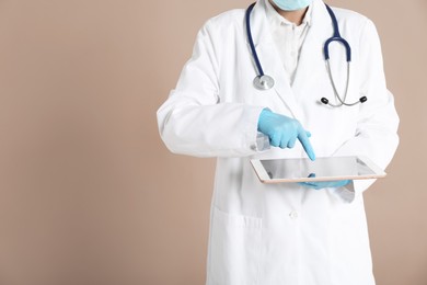 Photo of Doctor with tablet on beige background, closeup view. Space for text