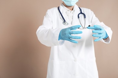 Photo of Doctor holding something on beige background, closeup