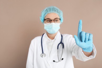 Doctor pointing at something on beige background, selective focus