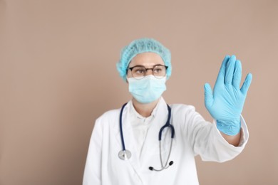 Doctor touching something on beige background, selective focus