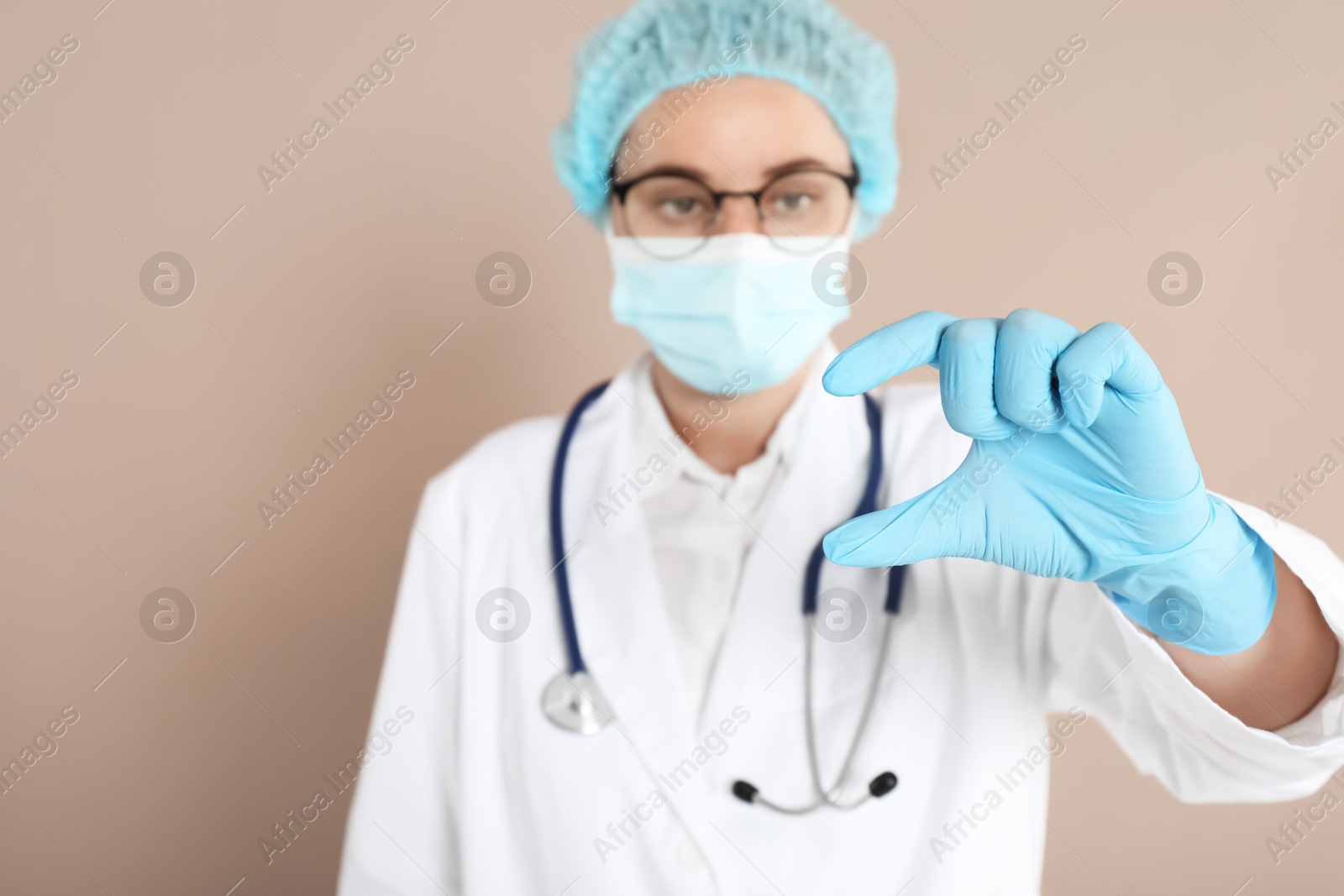 Photo of Doctor holding something on beige background, selective focus