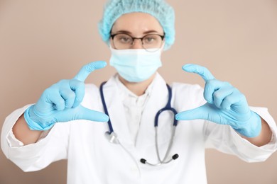 Doctor holding something on beige background, selective focus