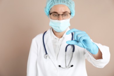 Doctor holding something on beige background, selective focus