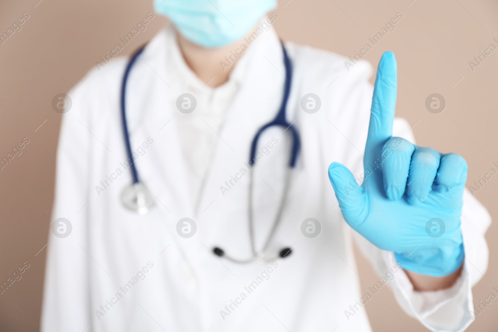 Photo of Doctor pointing at something on beige background, closeup