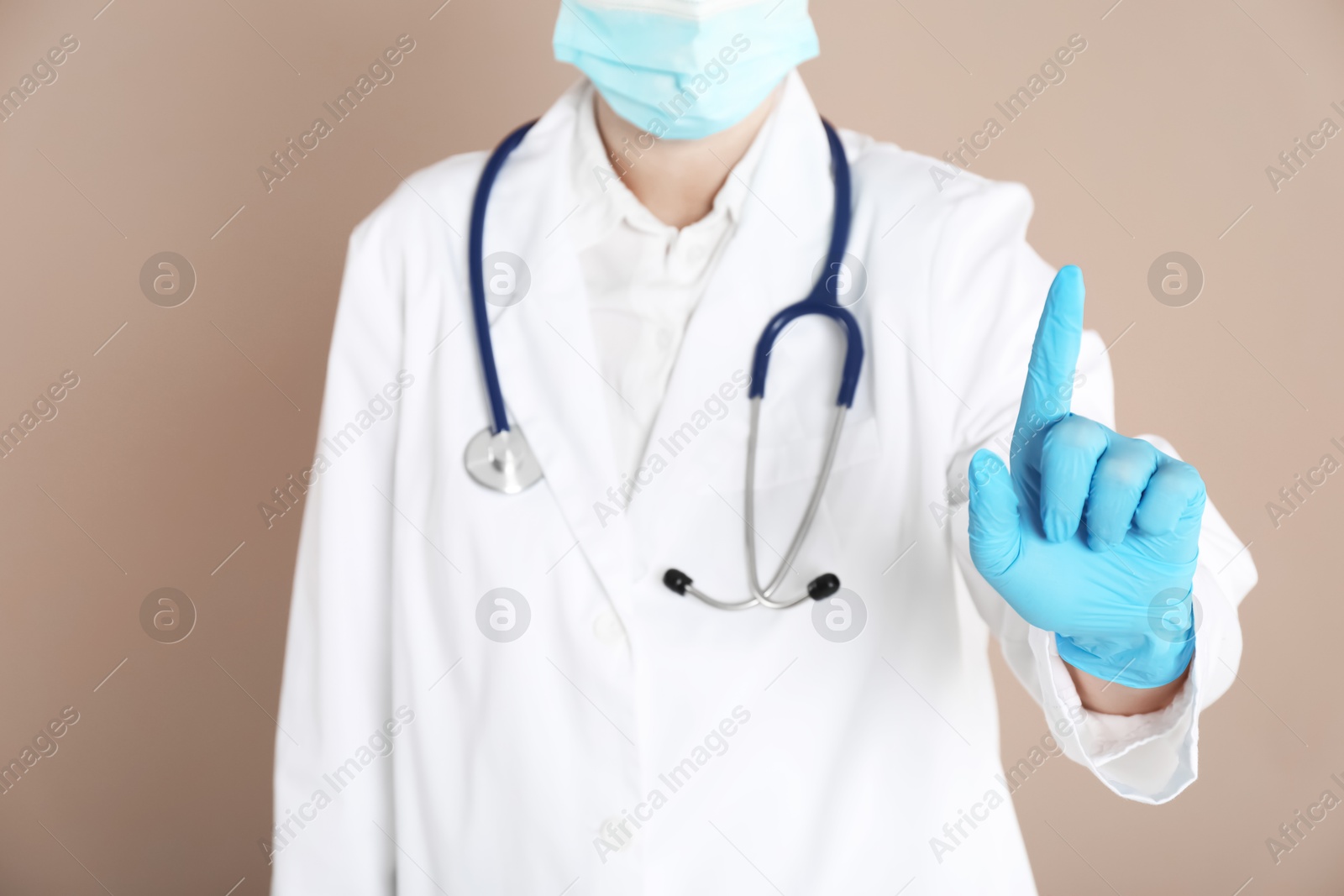 Photo of Doctor pointing at something on beige background, closeup