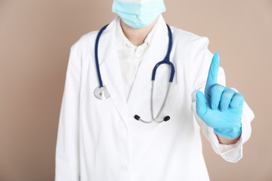 Photo of Doctor pointing at something on beige background, closeup