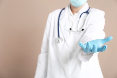 Photo of Doctor holding something on beige background, closeup