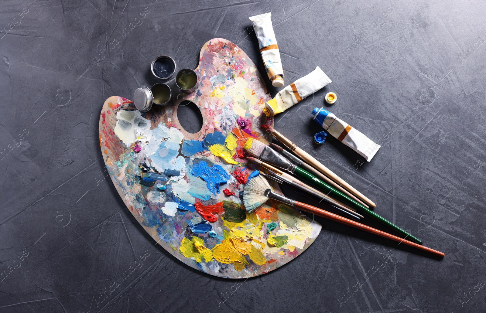 Photo of Artist's palette, brushes and paints on grey table, flat lay