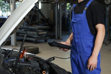 Photo of Auto mechanic doing car diagnostic at automobile repair shop, closeup