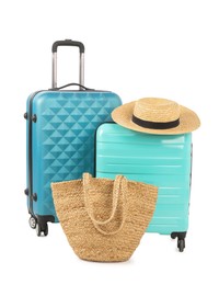 Photo of Light blue suitcases, bag and straw hat isolated on white