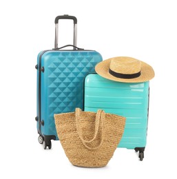 Photo of Light blue suitcases, bag and straw hat isolated on white