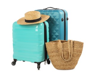 Photo of Light blue suitcases, bag and straw hat isolated on white