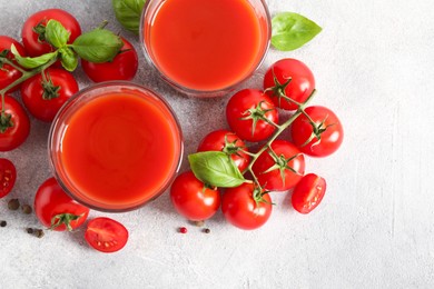 Tasty tomato juice in glasses, basil leaves, fresh vegetables and peppercorns on light grey table, flat lay