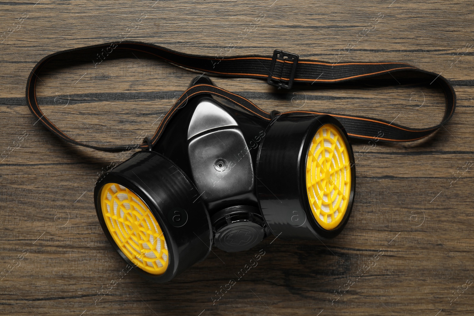 Photo of One respirator mask on wooden background, above view