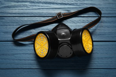 One respirator mask on blue wooden background, above view