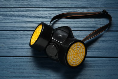 Photo of One respirator mask on blue wooden background, above view